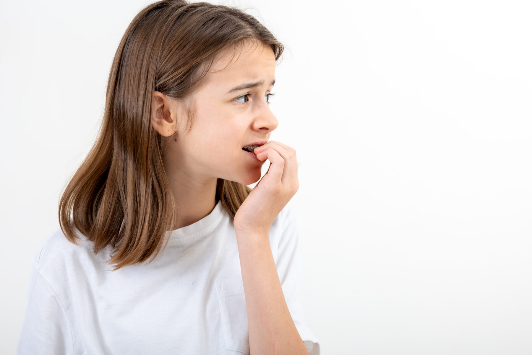 Scared and anxious girl, biting her fingernails on a white background isolated.